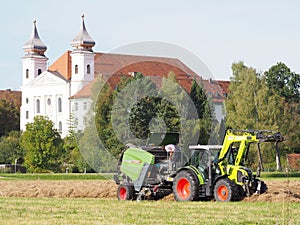 Hay harvest time, the farmer checks the hay bales tractor in front of Schlehdorf Abbey