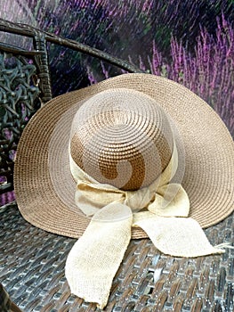 Hay hat and beautiful ribbin in garden chair in flower garden