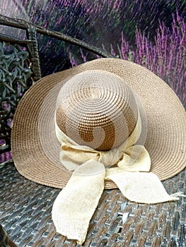 Hay hat and beautiful ribbin in garden chair in flower garden photo