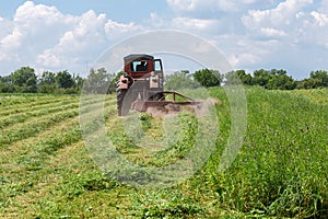 Hay mowing with tractor mounted rotary mower on a hayfield