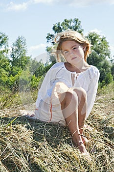 On the hay sits a little girl and to be sad