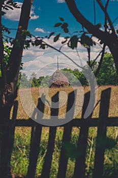 Hay stack framed with a old wooden fence and trees