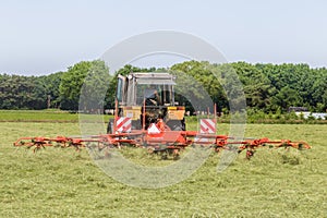 Hay truning to dry grass in the sun on the field in the Netherlands