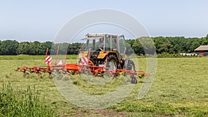 Hay truning to dry grass in the sun on the field in the Netherlands