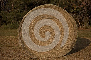 A Haybale Spiral in the Midwest setting sun on it.