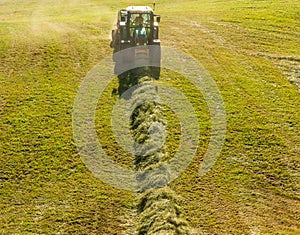 Haymaking on a hillside with rows of hay, a hay tedder and a hay-loader