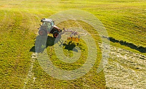 Haymaking on a hillside with rows of hay, a hay tedder and a hay-loader