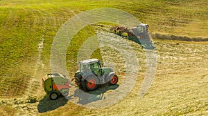 Haymaking on a hillside with rows of hay, a hay tedder and a hay-loader