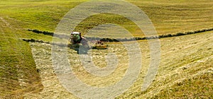 Haymaking on a hillside with rows of hay, a hay tedder and a hay-loader