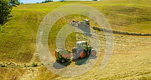 Haymaking on a hillside with rows of hay, a hay tedder and a hay-loader