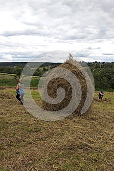 Haymaking season in Ukrainian Carpathian villages, women work in the field, throwing and raking hay by hand in the field