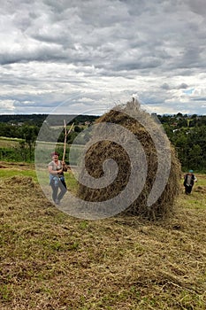 Haymaking season in Ukrainian Carpathian villages, women work in the field, throwing and raking hay by hand in the field