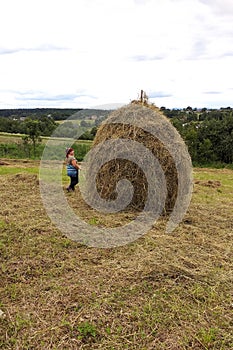 Haymaking season in Ukrainian Carpathian villages, women work in the field, throwing and raking hay by hand in the field