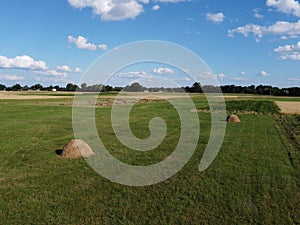 Haystack on a farm field on a sunny summer day, view from the top. Farm land, landscape from a bird`s eye view. Clear blue sky