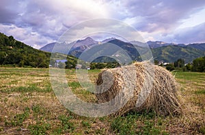 Haystack on the field with mountains on the background