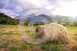 Haystack on the field with mountains on the background