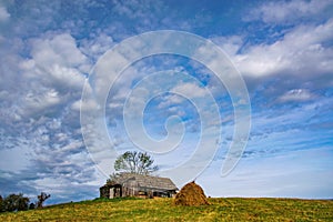 Haystack, mountain wooden hut and lonely tree on top of the hill under the picturesque sky, Borsa, Maramures, Romania