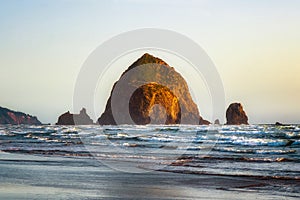 The Haystack Rock sea stack at high tide at sunset. Natural iconic landmark located in Cannon Beach, Oregon Coast