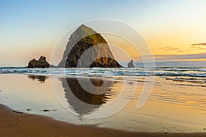 Haystack Rock at sunset with reflection on the sandy shore, Cannon Beach, Pacific Coast, Oregon, USA