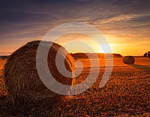 Haystack with the sun setting behind. Haystack in a field in Denmark with the sun setting behind photo