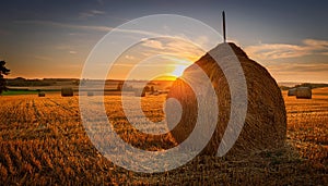 Haystack with the sun setting behind. Haystack in a field in Denmark with the sun setting behind photo