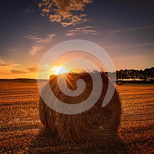 Haystack with the sun setting behind. Haystack in a field in Denmark with the sun setting behind photo