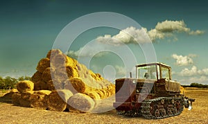 Haystacks on the field. old tractor and hay stack