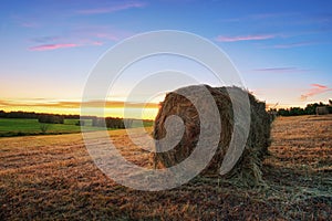 Haystacks and hay making in the fields in autumn at sunset