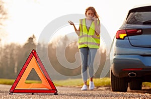 Hazard Warning Triangle Sign For Car Breakdown On Road With Woman Calling For Help 