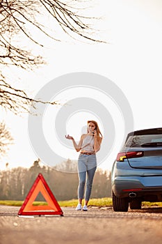 Hazard Warning Triangle Sign For Car Breakdown On Road With Woman Calling For Help