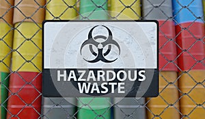 Hazardous waste sign on chain link fence. Oil barrels in background. 3D rendered illustration