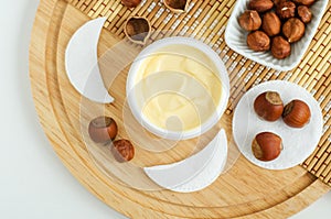 Hazelnut face cream in a small white jar and cotton pads. Homemade face mask, facial cleanser, body butter. Natural beauty