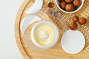 Hazelnut face cream in a small white jar and cotton pads. Homemade face mask, facial cleanser, body butter. Natural beauty