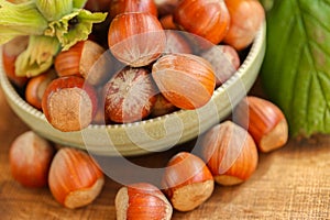 hazelnut harvest.Hazelnuts in a round green bowl with leaves close-up on a wooden table. Farmed organic ripe hazelnuts