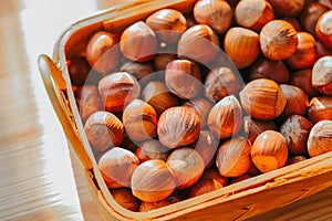Hazelnuts in a basket on a wooden table. Fresh harvest of hazelnuts. Farmed organic hazelnuts.