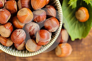 Hazelnuts close-up in a green cup on a wooden table. Whole nuts with green leaves. harvest of hazelnuts. Farmed organic