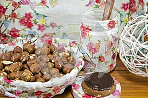 Hazelnuts in a decoupage decorated bowl on a table surrounded by