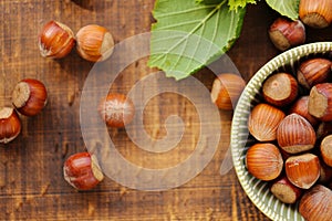 Hazelnuts in a green cup on a wooden table. Whole nuts with green leaves. harvest of hazelnuts. Farmed organic ripe