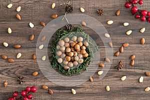 Hazelnuts in moss with badian and decorating elements on a wooden background.