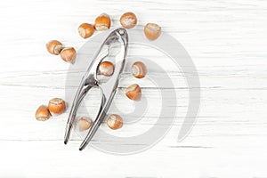 Hazelnuts and nutcracker on a white wooden background.