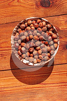 Hazelnuts in porcelain bowl on rustic wooden background. Raw fresh homegrowing nuts from house garden, weight loss diet