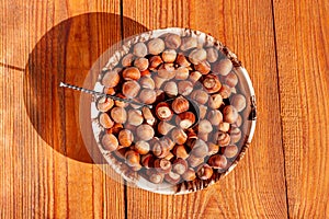 Hazelnuts in porcelain bowl on rustic wooden background. Raw fresh homegrowing nuts from house garden, weight loss diet