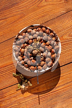 Hazelnuts in porcelain bowl on rustic wooden background. Raw fresh homegrowing nuts from house garden, weight loss diet