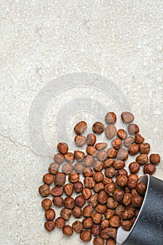 Hazelnuts on the table. A cup of hazelnuts flips over onto a marble top. Copy space. nuts in bulk lie on the table