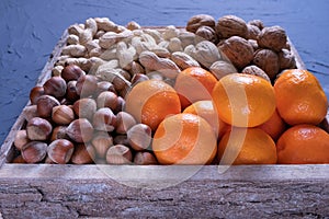 Hazelnuts, walnuts, peanuts and tangerines lie in a wooden box