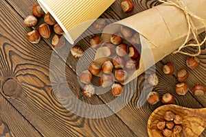 Hazelnuts on a wooden board. Nuts in kraft paper ,in a disposable eco-friendly glass, in an olive bowl, flat lay, copy