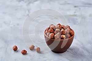 Hazelnuts in wooden bowl on wihite background with copy space, top view, selective focus.