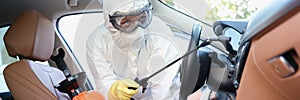 Hazmat female worker cleanse car interior with spray disinfectan