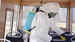 Hazmat team worker disinfects bus interior with antibacterial sanitizer on coronavirus covid-19 quarantine. Man in gas