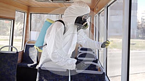 Hazmat team worker disinfects bus interior with antibacterial sanitizer wipes on coronavirus covid-19 quarantine. Man in